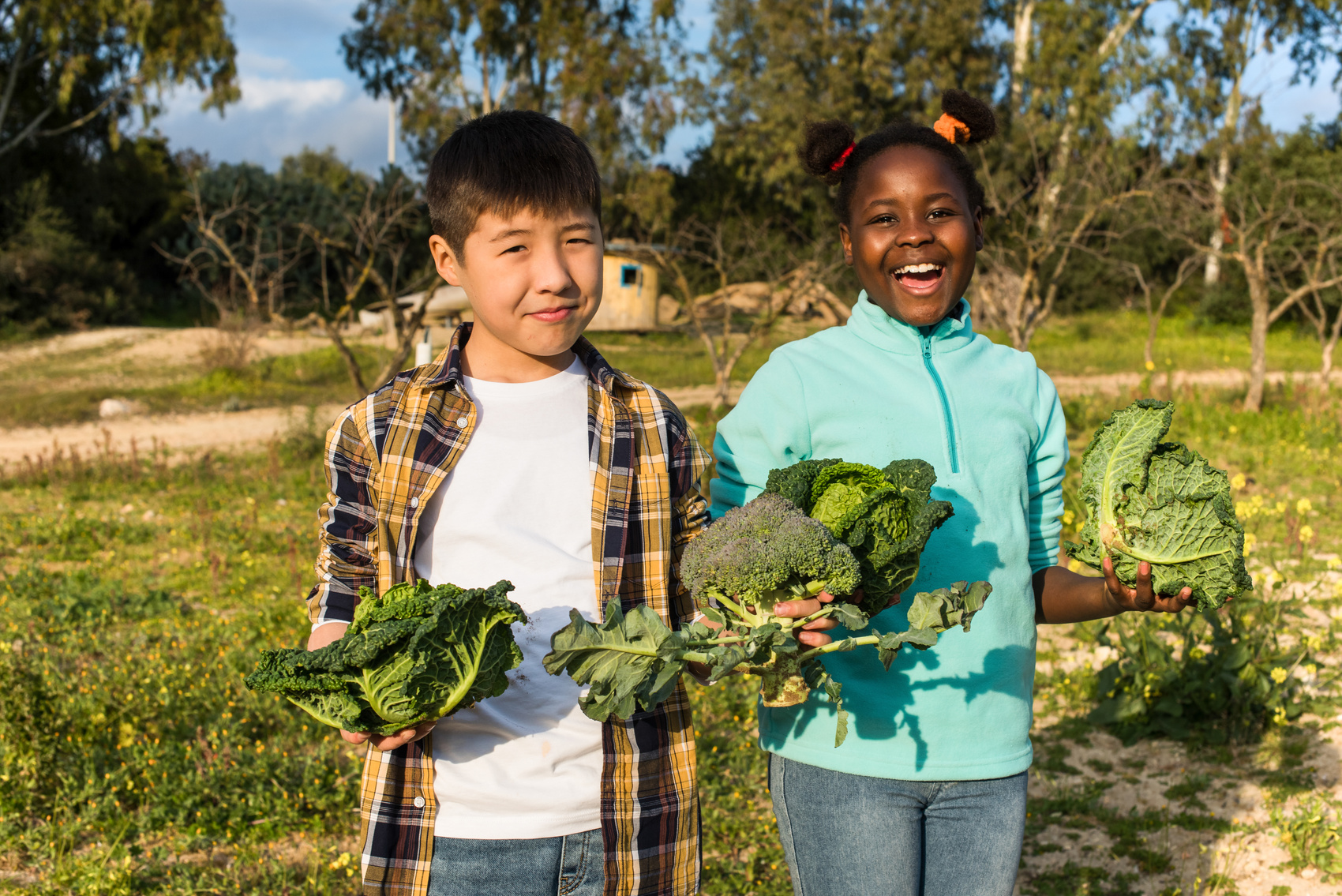 Two Diverse Children Happily Carrying Vegetables in Garden